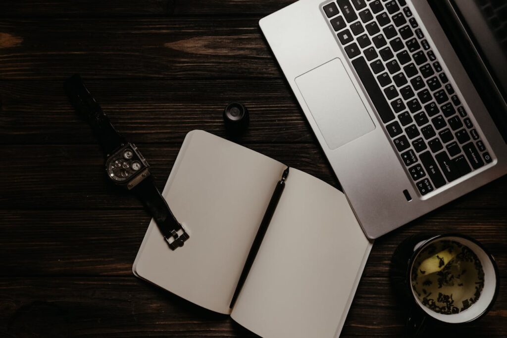 Flat lay of a productive workspace featuring a laptop, notebook, and a calming cup of tea.