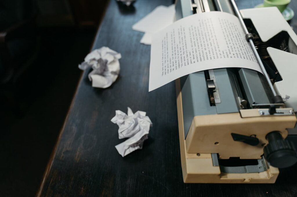 A close-up of a vintage typewriter with crumpled papers on a wooden desk, evoking a sense of creativity and nostalgia.